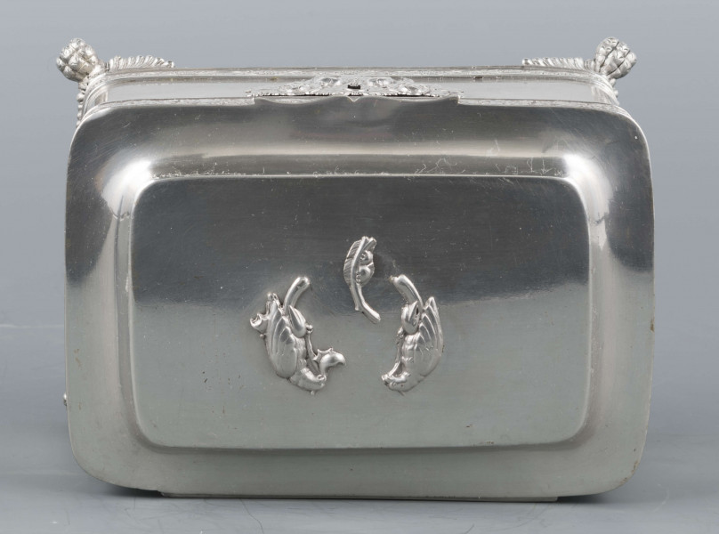 S/Mt/354/ML - Cukiernica prostokątna o lekko zaokrąglonych narożach, na czterech nóżkach w formie uskrzydlonych lwich łap, z profilowanym wieczkiem. Brzegi obwiedzione moletowaną taśmą: u dołu z motywem winnej łozy, u góry - wici różanej.Szyld zamka zdobi plakieta z girandą róż, druga - na wieczku - jest uszkodzona a przez to nieczytelna.
Na dnie sygnatury kursywa we wklesłych owalnych ramkach:
- K.Rotkiel
- w lublinie
Przedzielone okrągłą puncą z próbą 