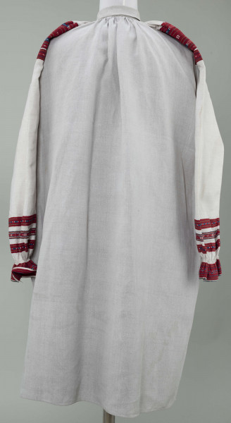 Koszula lniana o kroju przyramkowym, marszczonym. Ozdobiona na przyramkach i mankietach pereborami w kolorze czerwonym, granatowym i żółtym. Mankiety falbankami.