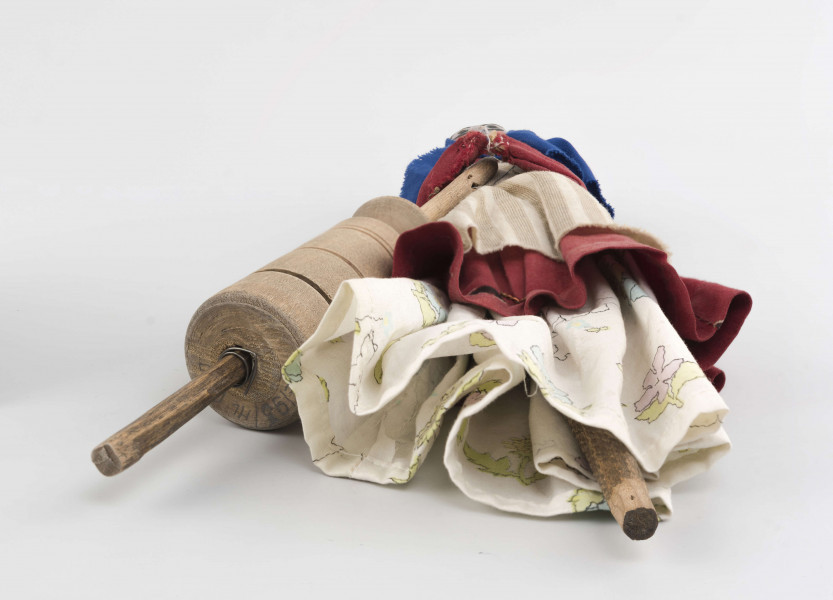 Kukiełka z szopki przedstawiająca czarownicę robiącą masło w maselnicy. Postać ubrana w jasną długą spódnicę, czerwony w koła kaftan i fartuch w szare pionowe pasy na jasnym tle. Na głowie ma granatową jedwabną chustkę wiązaną pod brodą. Twarz słabo modelowana, nos wystający, oczy namalowane farbą. Maselnica toczona, przyczepiona drutem do kukiełki.