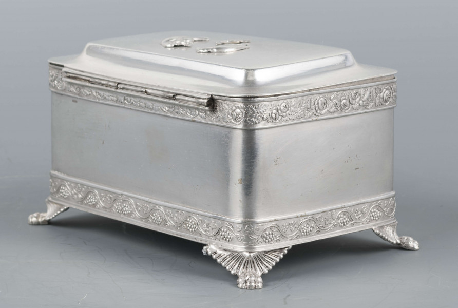 S/Mt/354/ML - Cukiernica prostokątna o lekko zaokrąglonych narożach, na czterech nóżkach w formie uskrzydlonych lwich łap, z profilowanym wieczkiem. Brzegi obwiedzione moletowaną taśmą: u dołu z motywem winnej łozy, u góry - wici różanej.Szyld zamka zdobi plakieta z girandą róż, druga - na wieczku - jest uszkodzona a przez to nieczytelna.
Na dnie sygnatury kursywa we wklesłych owalnych ramkach:
- K.Rotkiel
- w lublinie
Przedzielone okrągłą puncą z próbą 