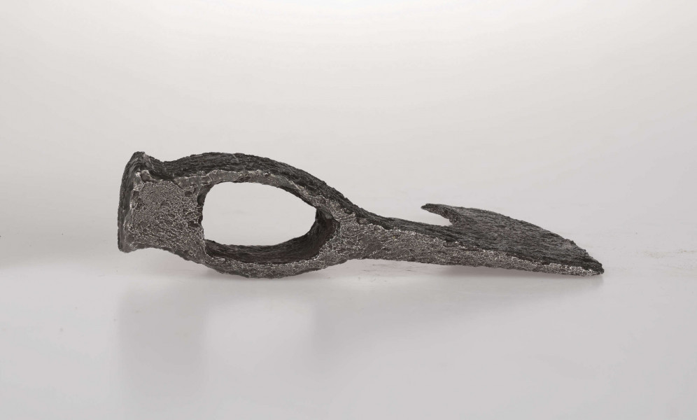 Czekan żelazny z guzowatym obuchem. Ostrze łukowato wygięte zakończone ukośnie ściętą brodą. Osada, szyjka i żeleźce zdobione obustronie pionowymi nacięciami wypełnionymi kratką z ukośnych nacięć Ornament na obu stronach różni sie nieco układem Na żeleźcu z jednej strony są umieszczone 5 nacieć w kształcie X