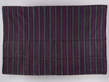 Tkanina pasiak tkana, zszyta z 2 części. Osnowa lniana, wątek wełniany. Splot rypsowy. Wielobarwna. Kolory: pomarańczowy (szer. 0,4 cm), zielony (szer. 2,5 cm), pomarańczowy (szer. 0,4 cm), fioletowy (szer. 2,5 cm), jasny amarantowy (szer. 0,3 cm), ciemny amarantowy (szer. 2,5 cm), jasny amarantowy (szer. 0,3 cm), fioletowy (szer. 2,5 cm), pomarańczowy (szer. 0,4 cm), zielony (szer. 2,5 cm). Używano jej do nakrywania łóżek.