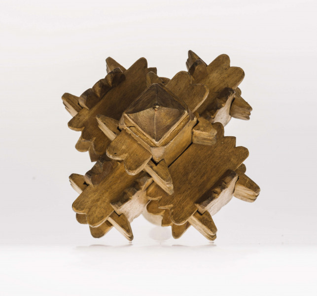 Grzechotka ta składa się z kawałeczków deseczki, rzeźbionych z brzegu i wycinanych w środku z jednej strony. Zrobiona jest bez kleju i gwożdzi. Deseczki te mają wymiary: dł. 4,5 cm szer. 2,2 cm grub. 0,5 cm. Jest ich 26. Tworzą one 6 