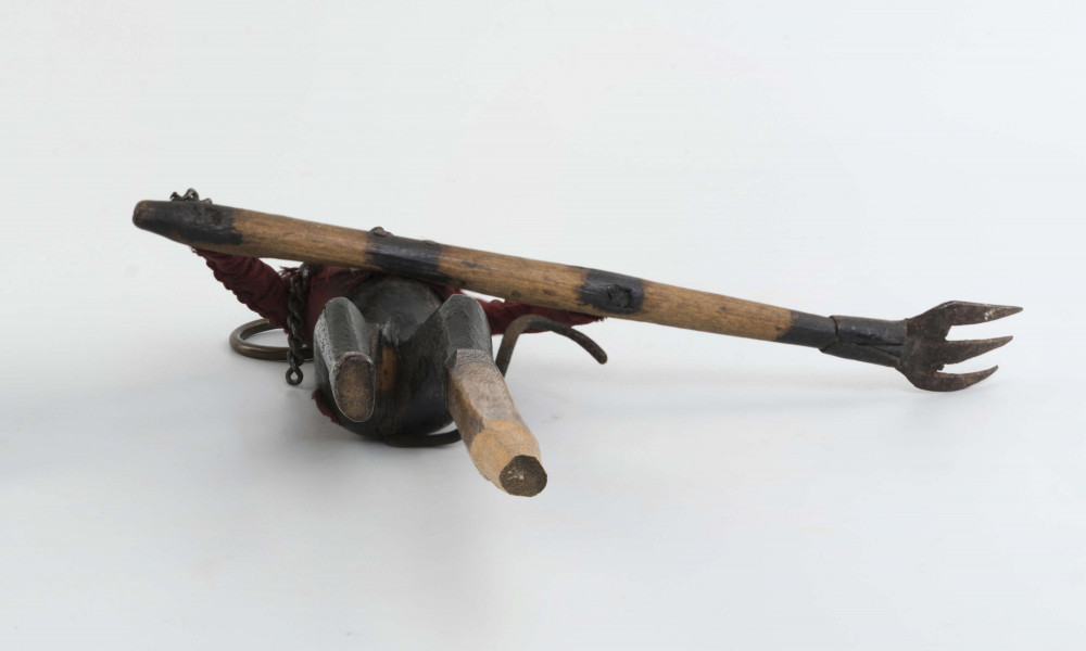 Figurka z szopki, diabeł, rzeźbiona w drewnie. Pomalowana na czarno. Ubrana w czerwony kaftan. Na szyi łańcuch. Do łańcucha doczepione widły, które diabeł trzyma obydwoma rękami. Twarz mocno modelowana, głębokie oczodoły, duże uszy, mała broda wysunięta mocno do przodu. Na głowie małe różki. Z tyłu skórzany ogon.