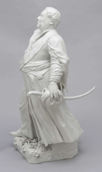 S/CS/657/ML - Figura z białej porcelany przedstawia króla Augusta III en pied na cokole zdobionym plastycznie modelowanymi różami i goździkami. Król stoi w kontrapoście, z lekko uniesioną głową, prawą rękę opiera na biodrze, w lewej opuszczonej trzyma czapkę okrągłą obszytą futrem. Ubrany jest w polski strój szlachecki: żupan, kontusz z zarzuconymi wylotami i pas. Na piersi ma order Złotego Runa i wstęgę z krzyżem orderu Orła Białego, przy lewym boku szablę na ozdobnych rapciach.
Figura stanowi wierne odwzorowanie portretu króla wykonanego przez Louis de Silvestre'a nadwornego malarza ok. roku 1737 (obecnie w zbiorach Muzeum w Wilanowie).