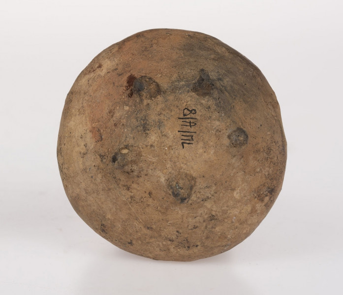 Flasza z kryzą. Szyjka lejkowato rozchylona o brzegu wywiniętym na zewnątrz i zaokrąglonej krawędzi wylewu, nieco powyżej nasady szyjki znajduje się kryza o zaokrąglonej krawędzi przechodząca w górny przyczep taśmowatego uszka; dolny przyczep ucha sięga połowy wysokości dwustozkowatego brzuśca, którego zaokrąglony załom przypada ok. 1/3 wys. naczynia (licząc od dna). Na obwodzie wklęsłego dna 5 niezbyt równomiernie rozmieszczonych guzków-nóżek. Surowiec-glina z drobnoziarnistym piaskiem. Barwa powierzchni zewnętrznej beżowo-ceglasta; wewnętrznej - beżowa. Przełom niewidoczny. Powierzchnia zewnetrzna gładzona, błyszcząca. Wypał dobry.