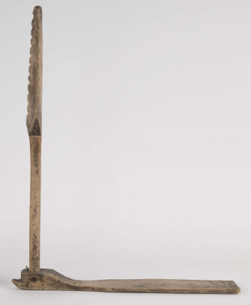 E/8397/ML - Przęślica łopatkowa z drewna. Składa się z cienkiej deski – przysiadki, w której przy jednym końcu osadzona jest pionowa beleczka zw. piórem, z nasadzonym od góry ruchomym krężlem w kształcie łopatki, zdobionej w ząbki.