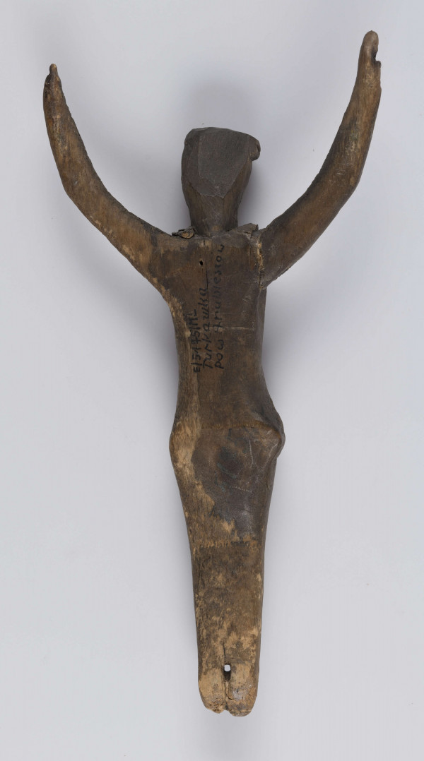 E/5175/ML - Rzeźba drewniana przedstawiająca Chrystusa Ukrzyżowanego. Głowa lekko pochylona. Twarz potraktowana schematycznie. Korona cierniowa w postaci opaski zdobionej rytem ukośnych rombów. Ręce łukowato wygięte ku górze, słabo zaznaczona klatka piersiowa, biodra silnie wystające, nogi lekko zgięte w kolanach, stopy słabo zaznaczone. Drewno prawdopodobnie lipowe. Figurka pęknięta wzdłuż. Brak krzyża.