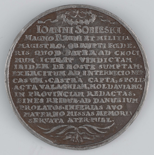 N/1535/ML - AV. Popiersie Sobieskiego: głowa na wprost, ramiona en trois - quarts w lewo. Po bokach w łukach napis:
PATRIAE SCUTUM - NATALE DETECTAE

RV. Pod wieńcem laurowym czternastowierszowy napis:
IOANNI SOBIESKI / MAGNO REGNI ET MILITIAE / MAGISTRO.  OB RUPTI FOEDE,, / RIS QUOD PATER AD CHOCI,, / MUM ICERAT VINDICTAM / IBIDEM DE HOSTE SUMPTAM. / EXERCITUM AD INTERNECIONEM / CAES UM CASTRA CAPTA. SPOLIA / ACTA VALACHIAM MOLDAVIAMQ / IN PROVINCIAM REDACTAS, / FINES REIPUB . AD DANUBIUM / PROLATOS . INFERIAS AVO / MATERNO MISSAS MEMORIA / SERVATA AETER . PUBL . 
Na dole związane palmy.