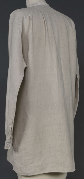 E/7980/ML - Koszula męska z lnianego, szarego płótna. Szyta ręcznie. Kołnierzyk to wąska oszewka z bawełnianego płótna. Z przodu rozcięcie zapinane na 3 guziczki wzmocnione plisą z podwójnego kawałka płótna. Rękawy długie, ujęte w mankiet, zapinany na guziczek. Pod pachami wszyte prostokątne kawałki tkaniny, zw. tokami.