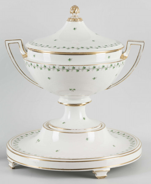 S/CS/1231/ML - Waza półkulista z przewężeniem poniżej wylewu, ucha łamane, stopa o okrągłej podstawie i wąskim trzonie wywiniętym u góry, pokrywa w formie wyniesionego stożka z plastycznym zwieńczeniem i uchwytem w kształcie szyszki. Dekoracja barwnie malowana i złocona: brzusiec, pokrywa i podstawa obwiedzione fryzem winorośli, na powierzchni rytmicznie rozrzucone pojedyncze liski, krawędzie, ucha i uchwyt pokrywy konturowane złotem, 
Podstawa w formie wyniesionego ściętego stożka z okrągłym wgłębieniem u góry, na trzech kostkowych nóżkach. 
 
