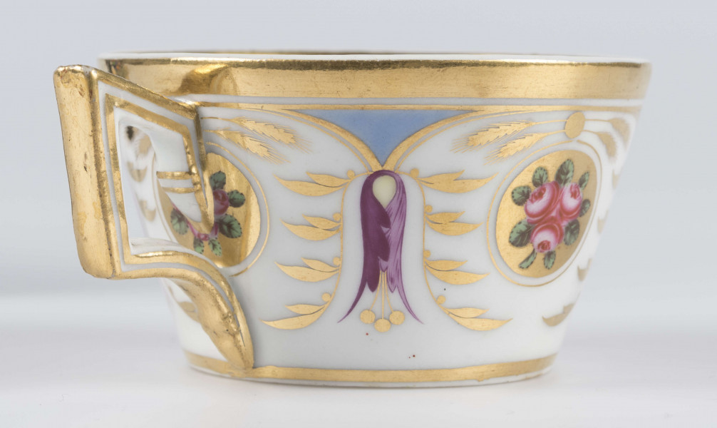 S/CS/1388/3/ML - Filiżanka koniczna, ucho łamane, profilowane, z przewiązkami w osadzeniach.  Dekoracja malowana wielobarwnie i złocona: brzusiec obiega szeroki fryz złożony ze stylizowanych ornamentów roślinnych (gałązek, kłosów zbóż i liści akantu)  połączonych z owalnymi medalionami, w których są trzy różowe różyczki z zielonymi listkami na złotym tle. Wylew złocony, złotym konturem obwiedzione ucho.
 