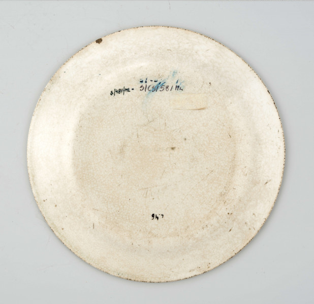 Talerz deserowy, okrągły, gładki, pokryty szkliwem białym, na nim dekoracja  drukowana w kolorze zieleni chromowej: w lustrze scena rodzajowa - kobieta z bawiącym sie dzieckiem; na kołnierzu szeroka bordiura z motywem ząbkowanej koronki, ornamentów wolutowych i kwiatów. 
 