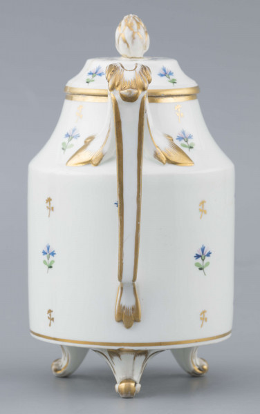 S/CS/1511/ML - Dzbanek cylindryczny, na trzech nóżkach w kształcie lwich łap, szyja w formie zwężonego pierścienia, wylew z dziobkiem, ucho dołem prostokątnie załamane, górą wygięte, rozdwojone, z reliefowymi liśćmi w osadzeniach. Przykrywa w formie wąskiego, konicznego pierścienia, z uchwytem w kształcie szyszki. Dekoracja malowana: regularny rzut drownych chabrów w kolorach błękitu i zieleni. Krawędzie,  ucho, dziobek, nóżki i uchwyt pokrywki konturowane złotem.
