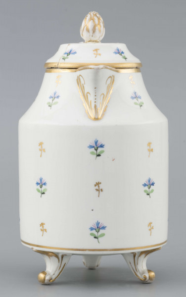 S/CS/1511/ML - Dzbanek cylindryczny, na trzech nóżkach w kształcie lwich łap, szyja w formie zwężonego pierścienia, wylew z dziobkiem, ucho dołem prostokątnie załamane, górą wygięte, rozdwojone, z reliefowymi liśćmi w osadzeniach. Przykrywa w formie wąskiego, konicznego pierścienia, z uchwytem w kształcie szyszki. Dekoracja malowana: regularny rzut drownych chabrów w kolorach błękitu i zieleni. Krawędzie,  ucho, dziobek, nóżki i uchwyt pokrywki konturowane złotem.
