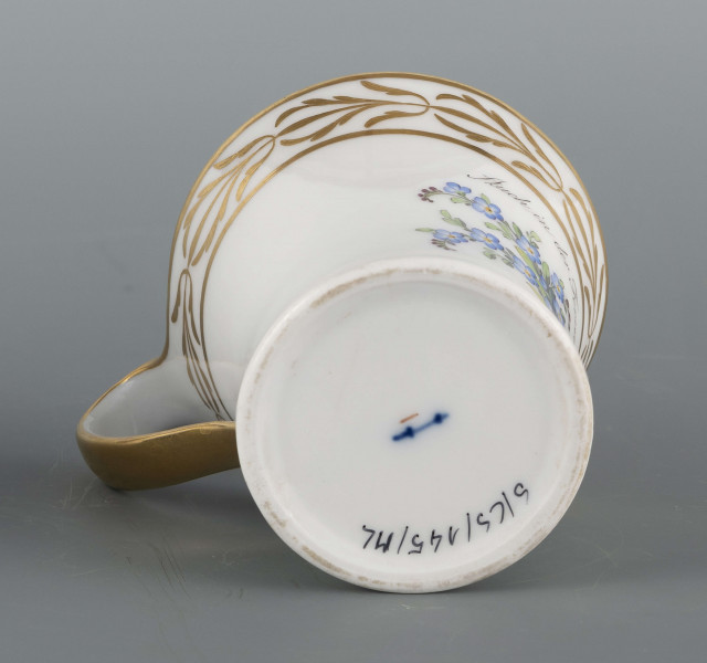 S/CS/145/ML - Filiżanka koniczna, ucho pętelkowe. Dekoracja malowana wielobarwnie i złocona. Frontalnie na białym tle malowany bukiet niezapominajek a nad nim napis złotem 