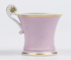 S/CS/133/1/ML - Filiżanka koniczna z rozchylonym wylewem, na niskiej stopie, ucho w formie pastorału z wolutą wyciągnietą ponad krawędź wylewu, zdobioną reliefową rozetką. Powierzchnia matowa malowana w całości na liliowy kolor, wylew obustronnie obwiedziony złotym paskiem, złotym konturem podkreślony brzeg stopy i profile ucha.

