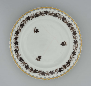 Talerz głęboki, okrągły,  krawędź zdobiona ażurem w postaci łańcuszka.  Dekoracja malowana brązem: na kołnierzu wić winorośli, w lustrze 3 regularnie rozmieszczone drobne gałązki, ażurowa krawędź podkreślona złotem.
 