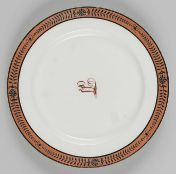 S/CS/1224/ML - Talerz płytki, okgły, gładki, przy krawędzi malowana bordiura ze stylizowanych czarnych gałązekprzedzielonych rozetkami,  na ceglastoczerwonym tle. W lustrze wiązany monogram 