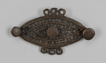 1396/A/ML/2 1396/A/ML/2 - Ażurowa fibula z brązu będąca elementem dwuczęściowej ozdoby. Na ornament składają się trzy koncentryczne listwy soczewkowate połączone ze sobą naprzemianlegle skośnymi, krótkimi poprzeczkami, tworzącymi trójkąty. Na dłuższej osi tarczki umieszczone są trzy symetrycznie guzki. Po środku dłuższych boków tarczki, naprzeciw siebie znajdują się potrójne uszka.