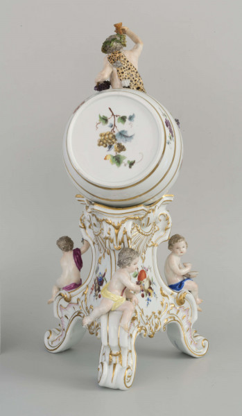 Grupa porcelanowa złoźona z dwóch elementów
1. beczka z siedzącym na niej Bachusem
2. podstawa zdobiona figurkami puttów