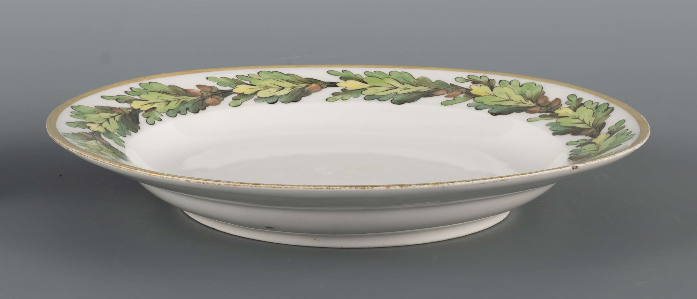 S/CS/1367/ML - Talerz płytki, okrągły, gładki. Kołnierz zdobiony malowanym otokiem dębiny z żołędziami; liście w tonacji zieleni morskiej z ciemnym konturem i rysunkiem wewnętrznym, żołędzie brązowe. Brzeg obwiedziony szerokim złotym  paskiem.
 