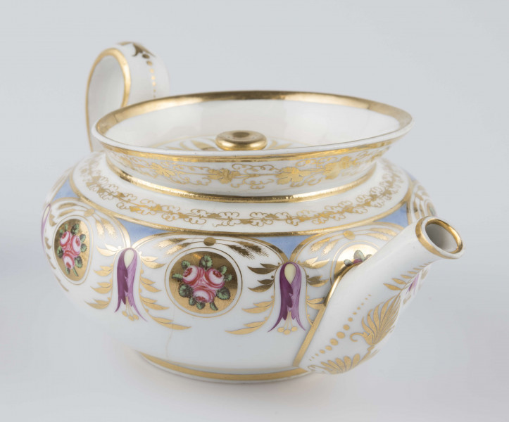 S/CS/1388/1/ML - Brzusiec w formie spłaszczonej kuli, ucho zaokrąglone wyciągnięte ponad górną  krawędź, dziobek lekko wygięty osadzony w dolnej połowie korpusu i uniesiony ku górze. Wokół wylewu wysoki kołnierz ze skośnym ścięciem wyżej uniesionym od strony dziobka, z odchylonymi na zewnątrz ściankami. Pokrywka płaska z uchwytem w postaci płaskiego guzika. Dekoracja malowana wielobarwnie i złocona: brzusiec obiega szeroki fryz złożony ze stylizowanych ornamentów roślinnych (gałązek, kłosów zbóż i liści akantu)  połączonych z owalnymi medalionami, w których są trzy różowe różyczki z zielonymi listkami na złotym tle. Krawędź górną i boki kołnierza obiega ornamentalna złota bordiura, na pokrywce stylizowana złota rozeta, złotym konturem obwiedzione wszystkie krawędzie.
 