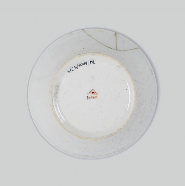 Spodek okrągły, wgłębiony, gładki. Dekoracja malowana wielobarwnie: w lustrze ptak siedzący na gałęzi (zięba ?), kołnierz  malowany na kremowożółty kolor, ujęty w złote paski.
 