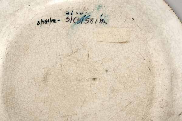 Talerz deserowy, okrągły, gładki, pokryty szkliwem białym, na nim dekoracja  drukowana w kolorze zieleni chromowej: w lustrze scena rodzajowa - kobieta z bawiącym sie dzieckiem; na kołnierzu szeroka bordiura z motywem ząbkowanej koronki, ornamentów wolutowych i kwiatów. 
 