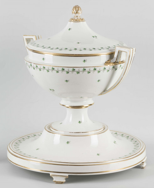 S/CS/1231/ML - Waza półkulista z przewężeniem poniżej wylewu, ucha łamane, stopa o okrągłej podstawie i wąskim trzonie wywiniętym u góry, pokrywa w formie wyniesionego stożka z plastycznym zwieńczeniem i uchwytem w kształcie szyszki. Dekoracja barwnie malowana i złocona: brzusiec, pokrywa i podstawa obwiedzione fryzem winorośli, na powierzchni rytmicznie rozrzucone pojedyncze liski, krawędzie, ucha i uchwyt pokrywy konturowane złotem, 
Podstawa w formie wyniesionego ściętego stożka z okrągłym wgłębieniem u góry, na trzech kostkowych nóżkach. 
 
