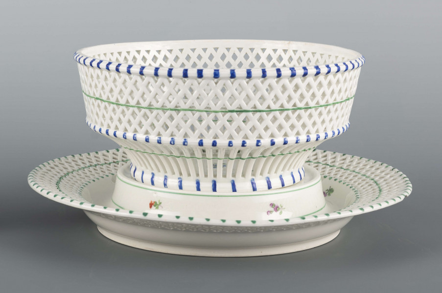 S/CS/1371/ML - Kosz konicznie wgłębiony, kołnierz ażurowy - w dolnej części pionowe równoległe pręty, w górnej ukośna kratownica), wylew obwiedziony półwałkiem. Dekoracja malowana barwnie: lustro obwiedzione wicią winorośli z trzema gałązkami niezapominajek, elementy koszykowe konturowane zielenią, krawędzie od zewnątrz podkreślone błękitnymi pionowymi kreskami.  