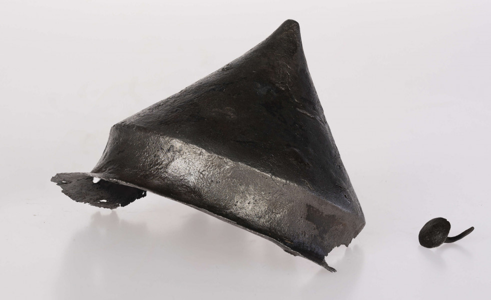 Umbo żelazne, stożkowate z zachowanym jednym płaskim nitem w brzegu. Stożek łagodnie zakończony.