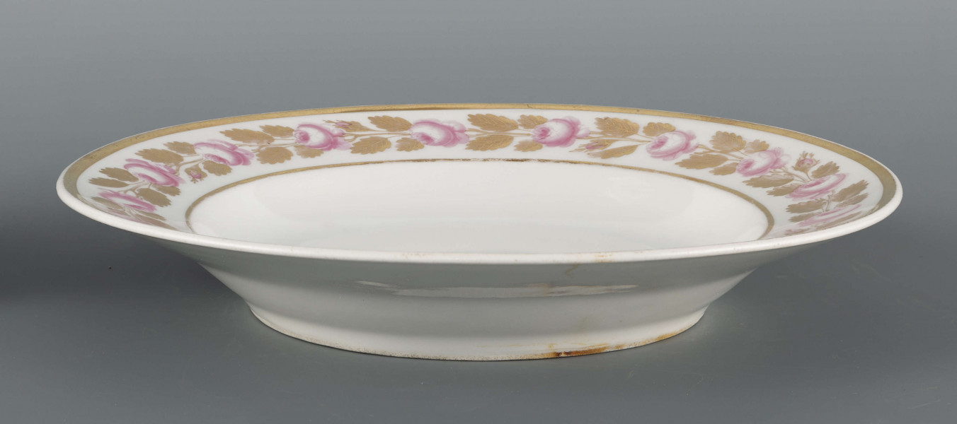 S/CS/1491/ML - Talerz płytki, okrągły, gładki. Kołnierz zdobiony malowaną girlandą różowych różyczek ze złotymi listkami ujętą w złote paski. Pośrodku lustra podwójne złote kółko.
 