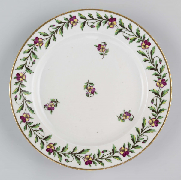 S/CS/1397/ML - Talerz płytki, okrągły, gładki, brzeg konturowany złotem. Kołnierz zdobiony malowaną girlandą bratków trójbarwnych z zielonymi łodyżkami, w lustrze regularnie rozmieszczone 4 pojedyncze kwiatki z listkami.
 