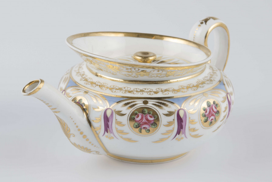 S/CS/1388/1/ML - Brzusiec w formie spłaszczonej kuli, ucho zaokrąglone wyciągnięte ponad górną  krawędź, dziobek lekko wygięty osadzony w dolnej połowie korpusu i uniesiony ku górze. Wokół wylewu wysoki kołnierz ze skośnym ścięciem wyżej uniesionym od strony dziobka, z odchylonymi na zewnątrz ściankami. Pokrywka płaska z uchwytem w postaci płaskiego guzika. Dekoracja malowana wielobarwnie i złocona: brzusiec obiega szeroki fryz złożony ze stylizowanych ornamentów roślinnych (gałązek, kłosów zbóż i liści akantu)  połączonych z owalnymi medalionami, w których są trzy różowe różyczki z zielonymi listkami na złotym tle. Krawędź górną i boki kołnierza obiega ornamentalna złota bordiura, na pokrywce stylizowana złota rozeta, złotym konturem obwiedzione wszystkie krawędzie.
 