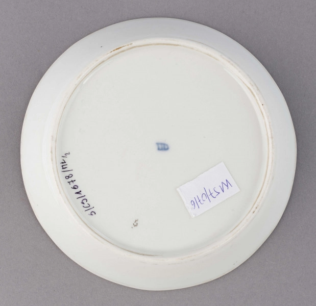 S/CS/1678/2/ML - Spodek okrągły, konicznie wgłębiony, brzeg złocony, złote kontury dzielą powierzchnię na ukośne pasy na przemian białe i jasnoszare. W nich malowane odpowiednio złote i czarne pióra w lustrze pośrodku złota rozeta.
 