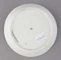 S/CS/1678/2/ML - Spodek okrągły, konicznie wgłębiony, brzeg złocony, złote kontury dzielą powierzchnię na ukośne pasy na przemian białe i jasnoszare. W nich malowane odpowiednio złote i czarne pióra w lustrze pośrodku złota rozeta.
 