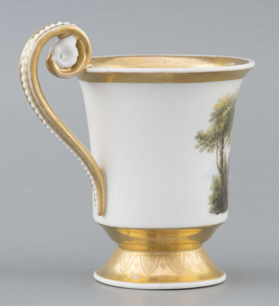 S/CS/1583/ML - Filiżanka koniczna, wylew lekko wywinięty, stopa w kształcie ściętego stożka, ucho wyciągnięte ponad wylew z rozetą  w górnym osadzeniu i wzorem perełek na powierzchni. Dekoracja malowana wielobarwnie: frontalnie na białym tle miniatura ze sceną parkową: od lewej drzewo, para spacerująca wokół gazonu, w głębi daleki pejzaż, na prawo stojąca rzeżba - personifikacja Sprawiedliwości z podpisem na cokole 