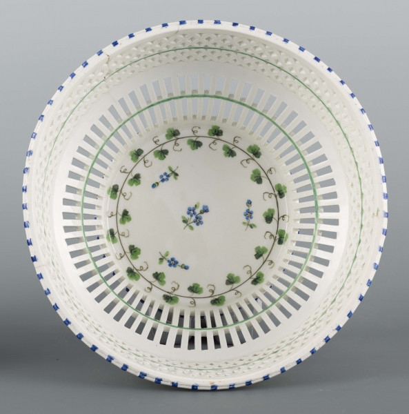 S/CS/1371/ML - Kosz konicznie wgłębiony, kołnierz ażurowy - w dolnej części pionowe równoległe pręty, w górnej ukośna kratownica), wylew obwiedziony półwałkiem. Dekoracja malowana barwnie: lustro obwiedzione wicią winorośli z trzema gałązkami niezapominajek, elementy koszykowe konturowane zielenią, krawędzie od zewnątrz podkreślone błękitnymi pionowymi kreskami.  