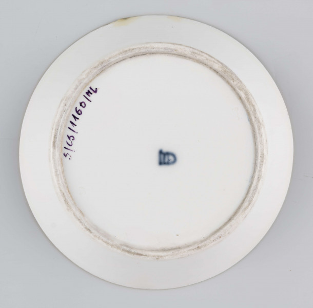 S/CS/1160/ML - Spodek okrągły, konicznie wgłębiony,  na nim bogata dekoracja w wypukłym złocie z ornamentów groteskowych, perełek i wzorów geometrycnych, ułożona w koncentryczne kręgi przedzielone wąskimi paskami jasnej zieleni, z rozetą pośrodku. Na kołnierzu wydzielone 3 migdałowate medaliony, wewnątrz nich mianiatury en grisaille na liliowym tle przedstawiające dwa połączone maszkarony 
  