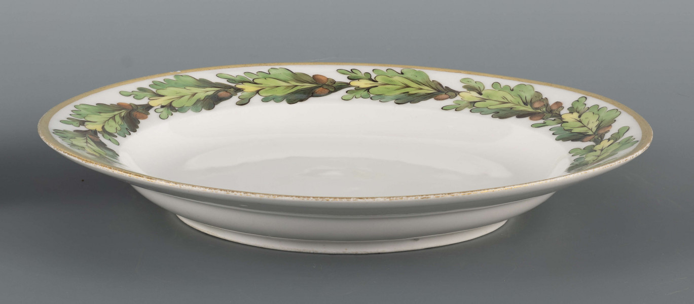 S/CS/1367/ML - Talerz płytki, okrągły, gładki. Kołnierz zdobiony malowanym otokiem dębiny z żołędziami; liście w tonacji zieleni morskiej z ciemnym konturem i rysunkiem wewnętrznym, żołędzie brązowe. Brzeg obwiedziony szerokim złotym  paskiem.
 