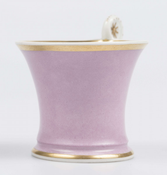 S/CS/133/1/ML - Filiżanka koniczna z rozchylonym wylewem, na niskiej stopie, ucho w formie pastorału z wolutą wyciągnietą ponad krawędź wylewu, zdobioną reliefową rozetką. Powierzchnia matowa malowana w całości na liliowy kolor, wylew obustronnie obwiedziony złotym paskiem, złotym konturem podkreślony brzeg stopy i profile ucha.
