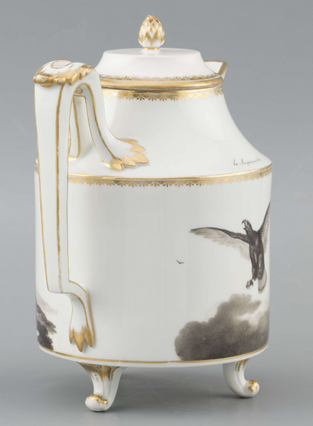 S/CS/1480/ML - Dzbanek cylindryczny, na trzech nóżkach w kształcie lwich łap, szyja w formie zwężonego pierścienia, wylew z dziobkiem, ucho dołem prostokątnie załamane, górą wygięte, rozdwojone, z reliefowymi liśćmi w osadzeniach. Przykrywa w formie wąskiego, konicznego pierścienia, z uchwytem w kształcie szyszki. Dekoracja drukowana en grisaille w kolorze czarnym. Po obu stronach brzuśca sceny alegoryczne: lew prowadzony na pasku przez amorka, powyżej napis 