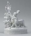 S/CS/1456/ML - Grupa figuralna z białej szkliwionej porcelany. Cokół owalny, wysklepiony z ornamentem opaskowym złożonym ze splecionych owali z rozetkami. Na nim siedzi naga kobieta (Venus) przed płonącym stosem o wysokich płomieniach i wyciągniętą w bok prawą ręką powstrzymuje nagie dziecko (Amorek) zapalające od ognia pochodnię, lewą ręką siega do ażurowego naczynia z ogniem. Za nią na powierzchni cokołu drobne roślinki.
