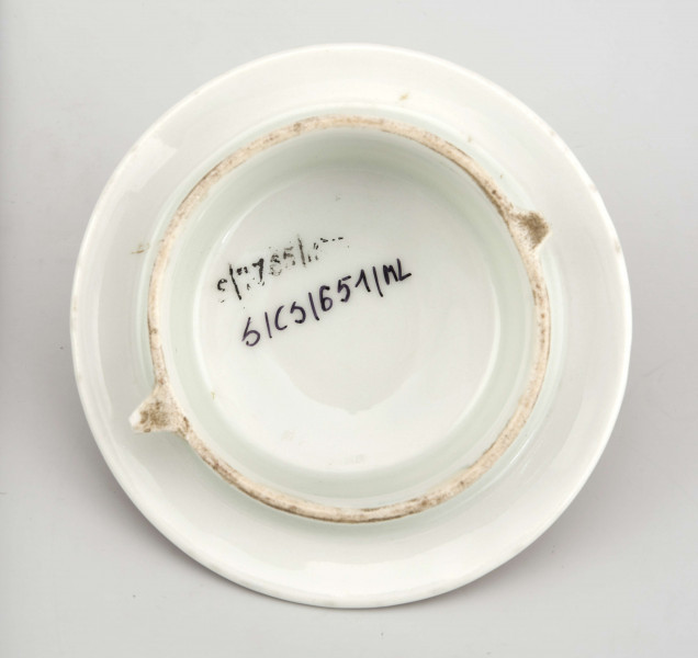 Imbryk w kształcie spłaszczonej kuli, na pierścieniowej podstawie, ucho prostokatnie łamane wyciągnięte ponad krawędź wylewu, dziobek wygięty esowato osadzony w połowie korpusu, pokrywka wysklepiona z uchwytem w formie cebulki. Powierzchnia pokryta zielonym półmatowym szkliwem, złocone ucho, dziobek, uchwyt pokrywki, krawędź wylewu, korpus obiega złocony fryz z wzorem wici liściastej na matowym tle. 
 