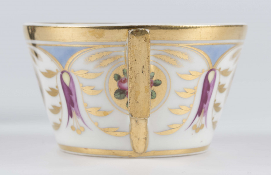 S/CS/1388/3/ML - Filiżanka koniczna, ucho łamane, profilowane, z przewiązkami w osadzeniach.  Dekoracja malowana wielobarwnie i złocona: brzusiec obiega szeroki fryz złożony ze stylizowanych ornamentów roślinnych (gałązek, kłosów zbóż i liści akantu)  połączonych z owalnymi medalionami, w których są trzy różowe różyczki z zielonymi listkami na złotym tle. Wylew złocony, złotym konturem obwiedzione ucho.
 