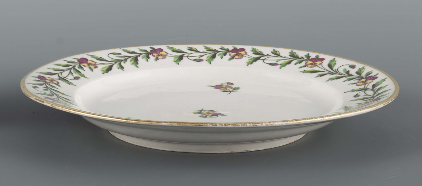 S/CS/1397/ML - Talerz płytki, okrągły, gładki, brzeg konturowany złotem. Kołnierz zdobiony malowaną girlandą bratków trójbarwnych z zielonymi łodyżkami, w lustrze regularnie rozmieszczone 4 pojedyncze kwiatki z listkami.
 