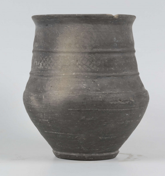 Dno płaskie, wyraźnie wyodrębnione stopką skośnie ściętą ku dołowi; dno wyodrębnione od części przydennej dookolnym wgłębieniem; lekko rozszerzające się ku górze, brzusiec łagodnie zaokraglony, ku górze zwężający się, przechodzący w wysoką, cylindryczną szyjkę; wylew płasko ścięty, rozchylony na zewnątrz; na największej wydętości brzuśca dookolny żłobek; w miejscu przejścia brzuśca w szyję i w połowie szyi dookolny wypukłe listwy; ucho z taśmy środkiem wklęsłej, biegnące od wylewu do załomu brzuśca, szyja zdobiona różnym ornamentem (trzy pasy) przez wygładzenie; powierzchnia gładzona, wyświecona
wymiary dodatkowe: 17,0 cm (obwód); 8,0 cm (śr. dna); 0,3 cm (wys. stopki); 0,5 cm (wys. szyi)