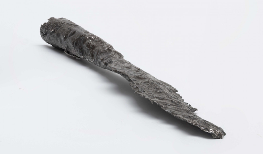 161/A/ML - Żelazny grot oszczepu. Ostrze laurowate, w przekroju soczewkowate z lekko zaznaczonymi żeberkami po obu stronach. Przejście w tuleję bardzo łagodnie wyprofilowane. Tuleja w przekroju nieznacznie spłaszczonego koła, rozszerzająca się ku końcowi. Wewnątrz tulei zachowane resztki drzewca. 
