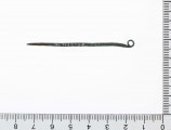 1562/A/ML - Szpila brązowa z drutu o przekroju okrągłym. Główka rozklepana i zawinięta w uszko. Surowiec - brąz. Sposób wykonania - kucie. Stan zachowania - dobry. 